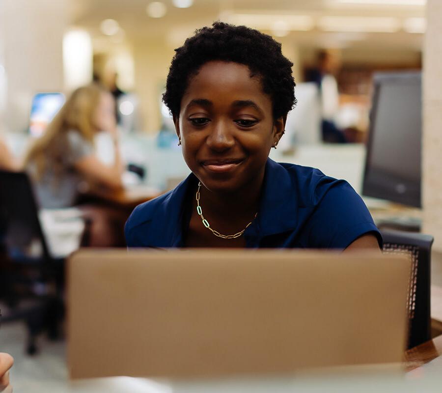 A PBA student works on a laptop in the library.